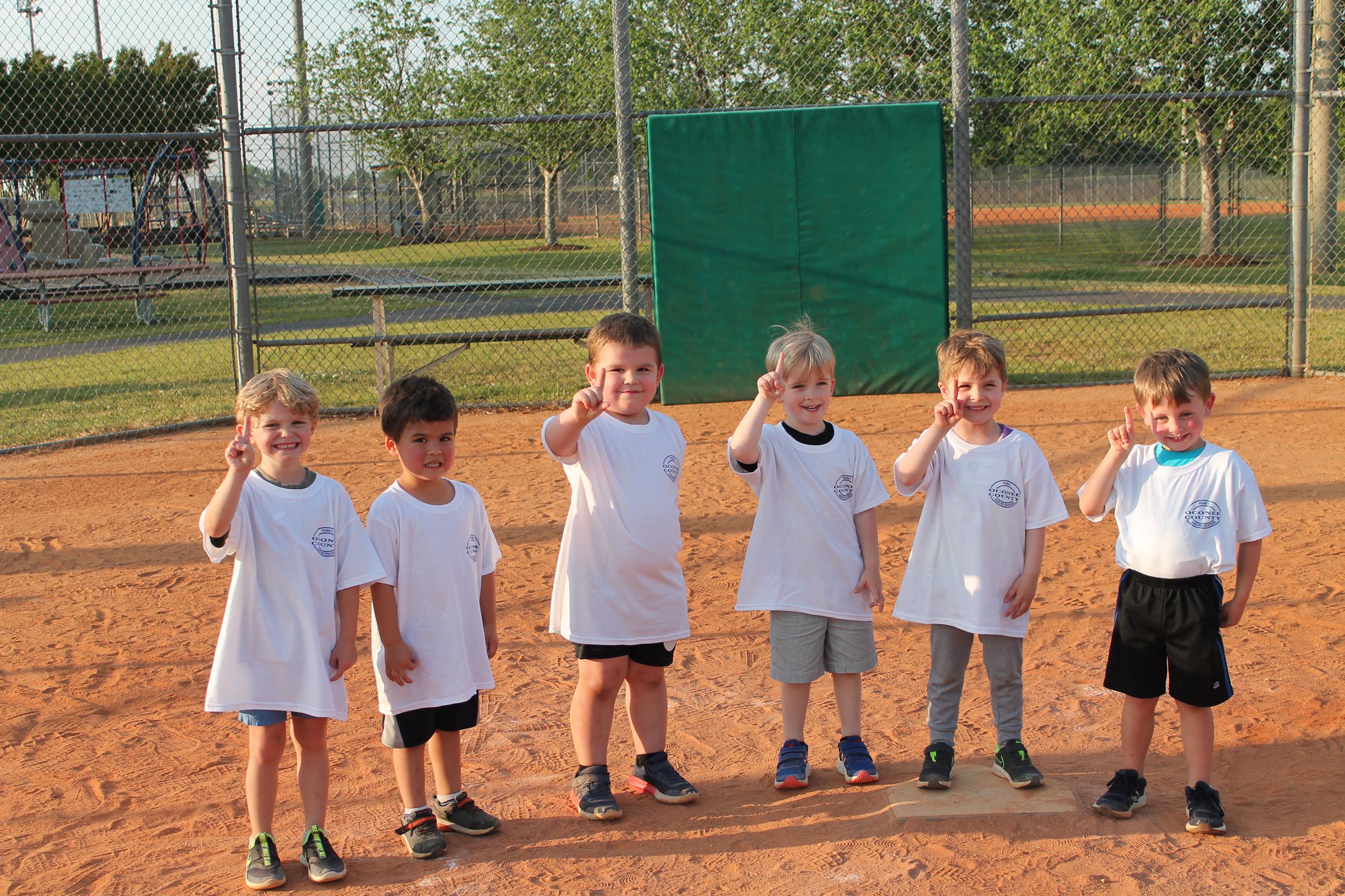 Boys holding up one finger on baseball field