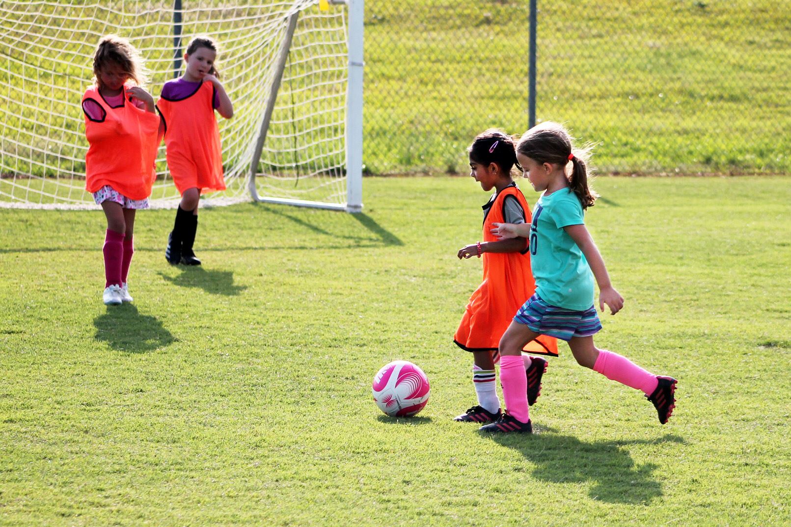 four girls playing soccer on field
