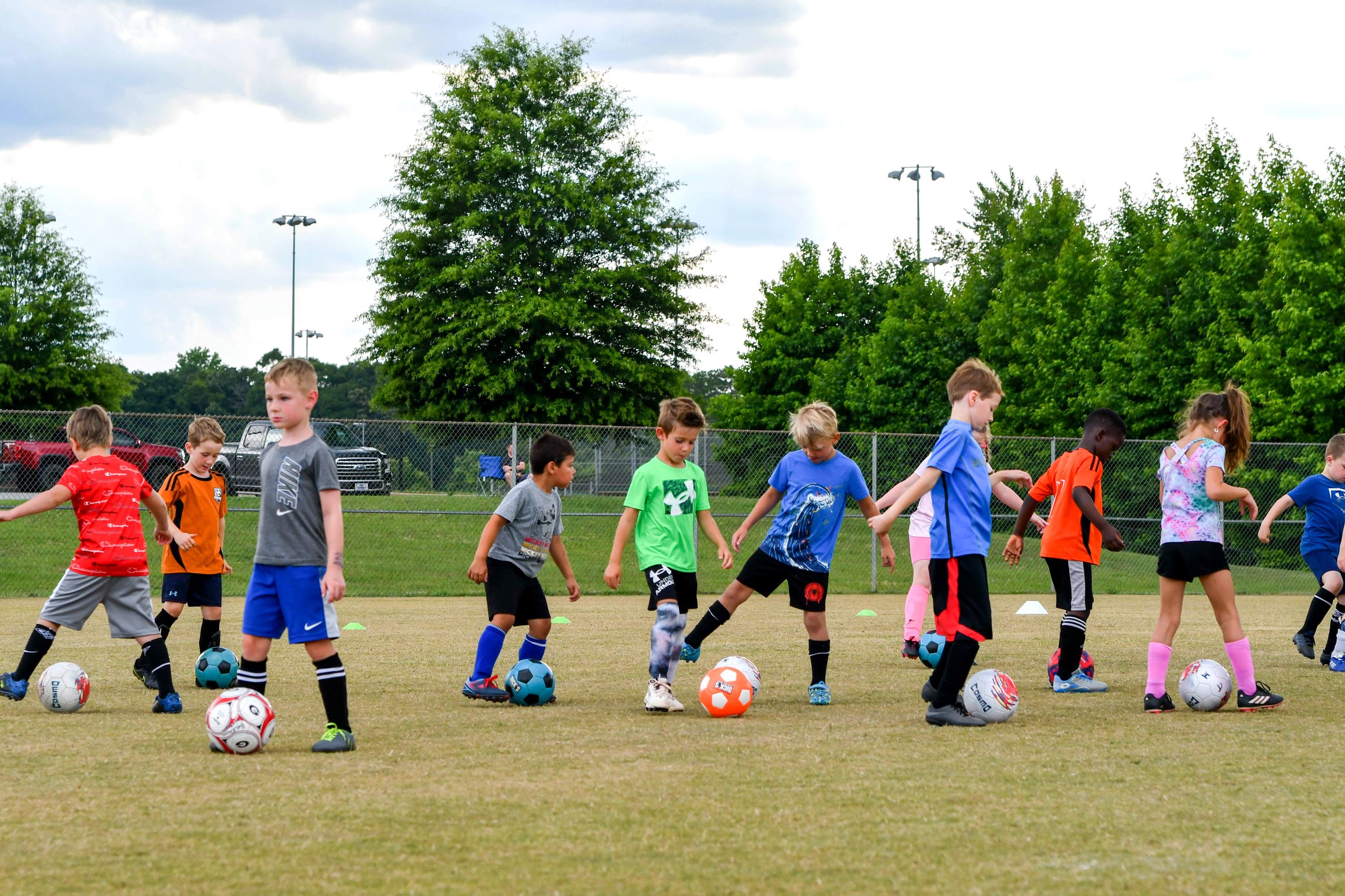 Boys and girl practicing dribbling soccer balls